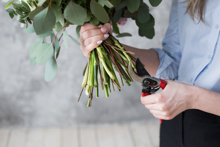 Florist at work: pretty young woman making fashion modern bouquet of different flowersの写真素材