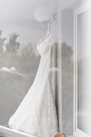 Beautiful wedding dress on hanger in room. the light from the windowの写真素材