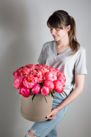 girl holding beautiful mix coral and pink flower bouquet in round box with lid. peonies grade Coral Sharm.の写真素材