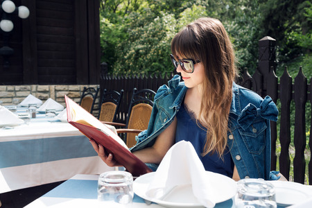 A smiling woman in a restaurant with the menu in handsの写真素材