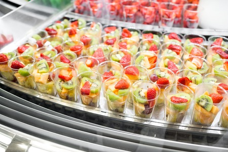 Fruit salad arranged in plastic cups for sale. refrigerator showcase or buffet. Used in cocktails and as a topping to the chocolate fountain. Selective focusの写真素材