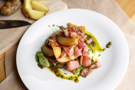 Fried potato with bacon and green beans on plate over wooden background. selective focus