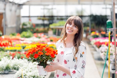Young woman buying flowers at a garden centerの写真素材