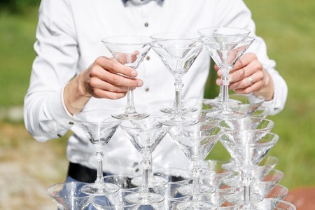 Waiter builds a pyramid of glasses for champagneの写真素材
