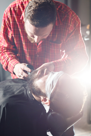 Barber making beard haircut using shaverの写真素材