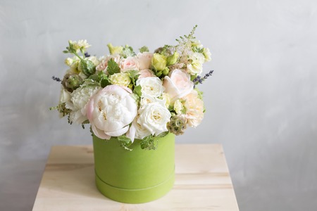 Beautiful tender bouquet of flowers in green box on light-gray background with space for textの写真素材