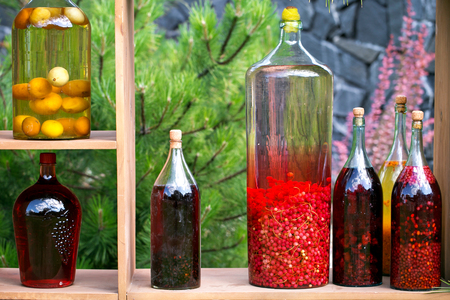 Tincture bottles of lemon, currant, berries and rowanberries. Herbal medicine. A strong alcoholic drinkの写真素材