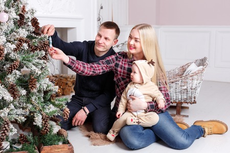Happy family at Christmas. The parents and the baby sitting on the floor and smiling.の写真素材