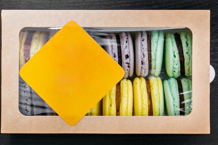 Colorful french macaroons or macarons on black wooden table. Space for text.