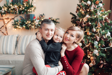 Portrait of young friendly family looking at camera on Christmas morning. Father, mother and daughterの写真素材