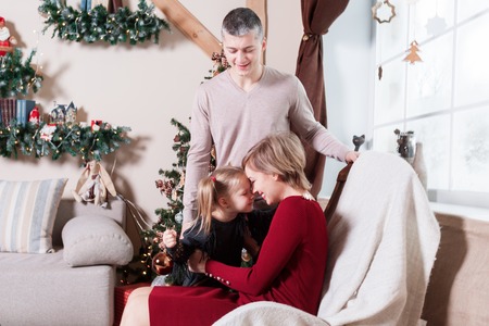 Portrait of young friendly family on Christmas morning. Father, mother and daughterの写真素材