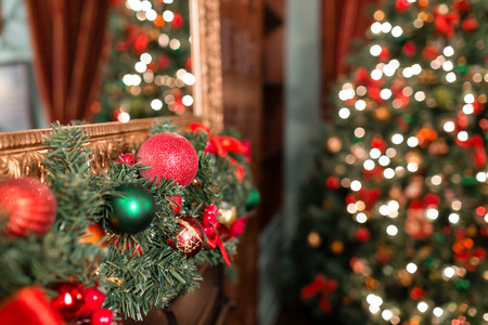 Closeup of red and green bauble hanging from a decorated Christmas branch. abstract background with defocused lightsの写真素材