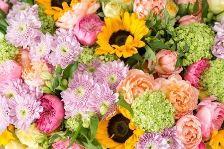 beautiful bouquet of mixed flowers in a vase on wooden table. the work of the florist at a flower shop. a bright mix of sunflowers, chrysanthemums and roses.の写真素材