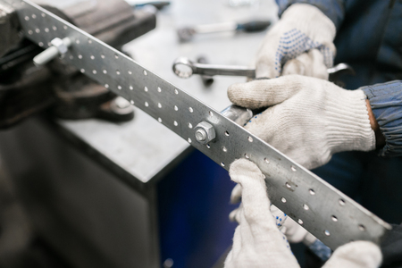 Childrens master class in the auto service. Iron Wrench in hand unscrews the large hex bolt. The wrench steel tools for repairの写真素材