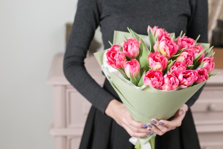 beautiful luxury bouquet of pink tulips flowers in woman hand. the work of the florist at a flower shop.の写真素材