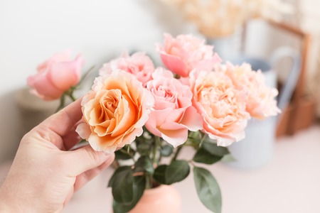 hand touches. Bouquet flowers of pink roses in glass vase. Shabby chic home decor. florist at a flower shop.の写真素材