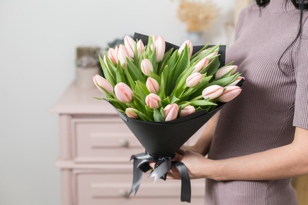 beautiful luxury bouquet of pink tulips flowers in woman hand. the work of the florist at a flower shop.の写真素材