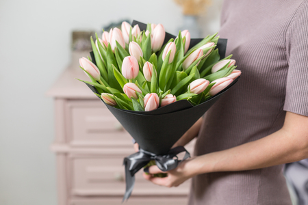 beautiful luxury bouquet of pink tulips flowers in woman hand. the work of the florist at a flower shop.の写真素材