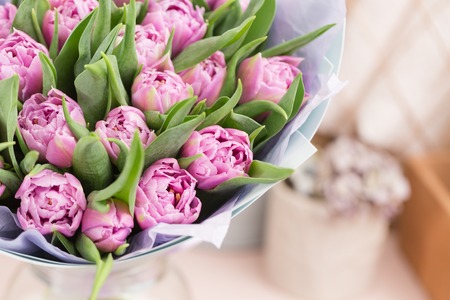 close-up. beautiful luxury bouquet of lilac tulips flowers on table. the work of the florist at a flower shop.の写真素材