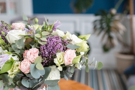 Sunny spring morning in living room. Beautiful luxury bouquet of mixed flowers in glass vase on...