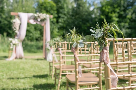 Wooden chairs decorated with flowers, are in the zone of the wedding ceremony in a pine forestの写真素材
