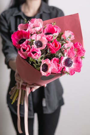 cute flowers. beautiful bouquet of pink anemones in woman hand. the work of the florist at a flower shop. A small family businessの写真素材