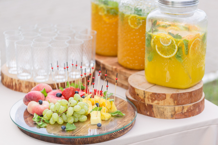 Glass bank of lemonade with sliced citrus fruits on a buffet table. Summer party outdoor. Detox.の写真素材