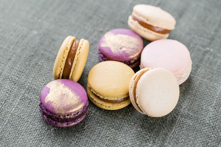 Close-up colorful French or Italian macaron on white wooden table. Macarons is French dessert served...