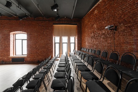 Loft style. Hall with black chairs for webinars and conferences. A huge room with large Windows,...