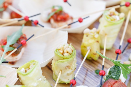 Zucchini rolls with pine nuts. Pesto sauce. Tasty buffet table. Summer party outdoor.の写真素材