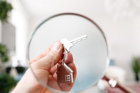 Holding house keys on house shaped keychain closeup. Concept of real estateの写真素材