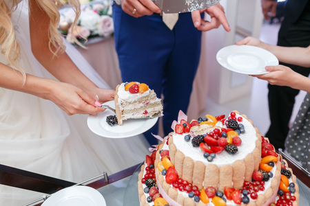 Wedding cake with berries. Bride and groom cut sweet cake on banquet in restaurant.の写真素材