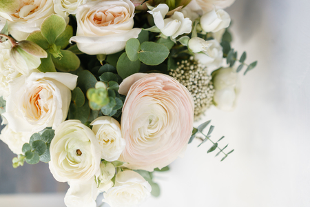 Wedding bouquet of white roses and buttercup on a wooden table. Lots of greenery, modern asymmetrical disheveled bridal bunchの写真素材