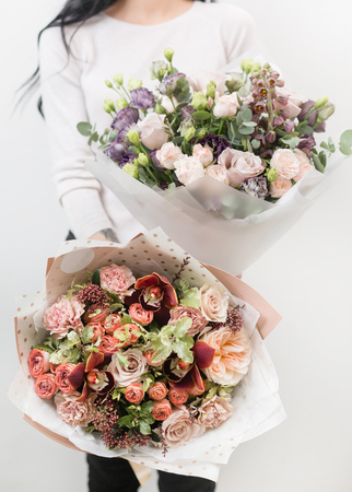 two bouquet of beautiful flowers in womens hands. Floristry concept. Spring colors. the work of the florist at a flower shop. Vertical photoの写真素材
