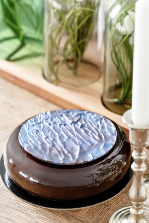 Luxury round chocolate dessert, with a blue disk on Black glaze. Mousse birthday cake with decor. on a wooden tableの写真素材