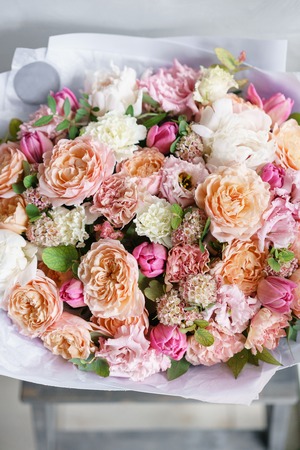 beautiful luxury bouquet of mixed flowers in woman hand. the work of the florist at a flower shop. Vertical photoの写真素材