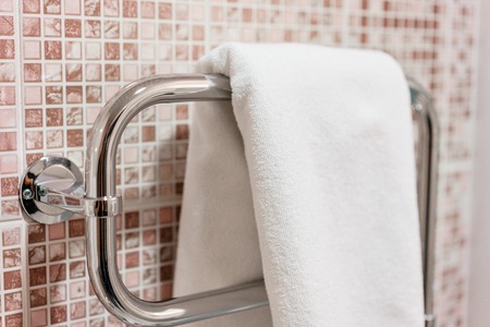 Clean white towel and bathrobe on a hanger prepared to use. Bathroom Inside rooms of a apartment or hotel.の写真素材