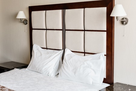 Modern double bedroom. Comfortable soft white pillows on a bed. Inside rooms of a apartment or hotel.の写真素材