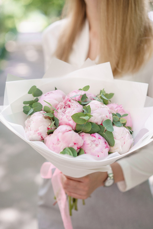 peonies. Young girl holding a flower. Beautiful summer bouquet. Arrangement with mix flowers peony. The concept of a flower shop. Content for the catalogの写真素材