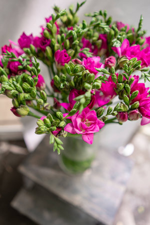 bright pink freesia flowers in glass vase on wooden table. Beautiful summer bouquet. Arrangement with mix flowers. The concept of a flower shop. Content for the catalogの写真素材