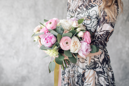 close-up beautiful bouquet with peonies decorated with ribbons. Young Girl holds a luxurious summer bouquet. The concept of the celebration or flower shop. looking at the cameraの写真素材