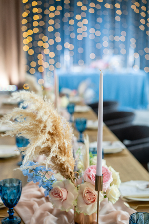 Beautiful and exquisite decoration of the wedding celebration. Banquet served table with a beige pink tablecloth, plates and candlesticks with candles.の写真素材
