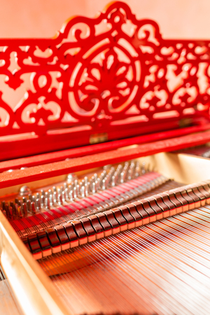 Strings inside a red grand piano. Piano playing, dampers, felt hammers, bronze strings and metal frame.の写真素材