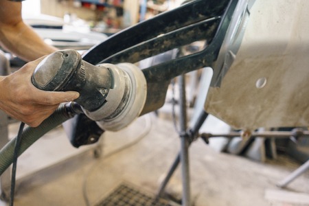The mechanic works with a grinding machine. Garage painting car service. Repairing car section after the accident.の写真素材
