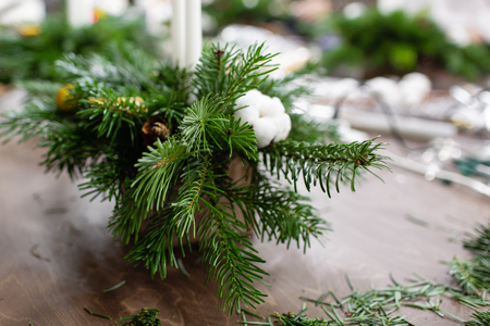 A woman decorates a Christmas arrangement with candles. Hands close-up. Master class on making decorative ornaments. Christmas decor with their own hands. The new year celebration. Flower shopの写真素材