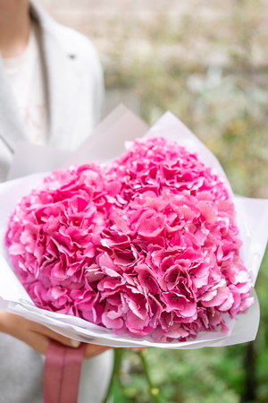 pink hydrangea. Young girl holding a flower arrangement. Beautiful summer bouquet. The concept of a flower shop. Content for the catalogの写真素材