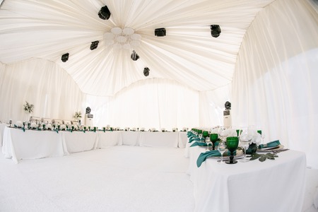 Beautiful banquet hall under a tent for a wedding reception. Interior of a wedding tent decoration ready for guests. Decor flowers. Green themeの写真素材