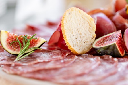 Food tray with delicious salami, pieces of sliced ham, sausage. Cutting sausage and cured meat on a celebratory table.の写真素材