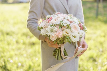 Young girl holding a beautiful spring bouquet. flower arrangement with garden roses. Color light pink. Bright dawn or sunset sunの写真素材
