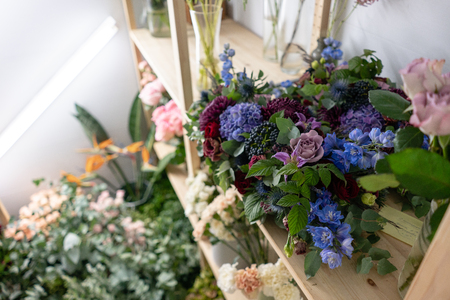Flower shop concept. Different varieties fresh spring flowers in refrigerator room for flowers. Bouquets on shelf, florist business.の写真素材